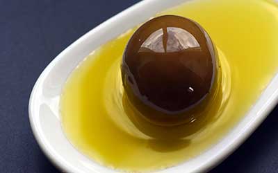 Löffel mit einer in Öl gebadeten Olive