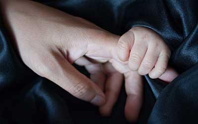 Kategoriedetails Muttertag, Sie sehen die Hand einer Mutter, die die ihres Babys h&auml;lt.