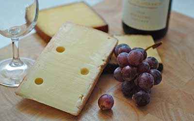 cheese board next to grapes and wine