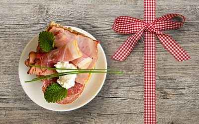 assiette avec jambon à côté de l'arc de cadeau avec des boîtes.