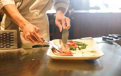 cook handling ham on a plate.